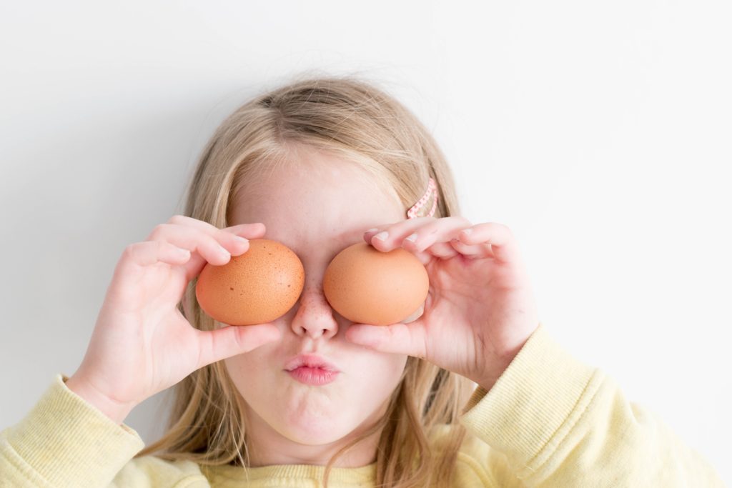 dziewczynka zasłaniająca oczy kurzymi jajkami